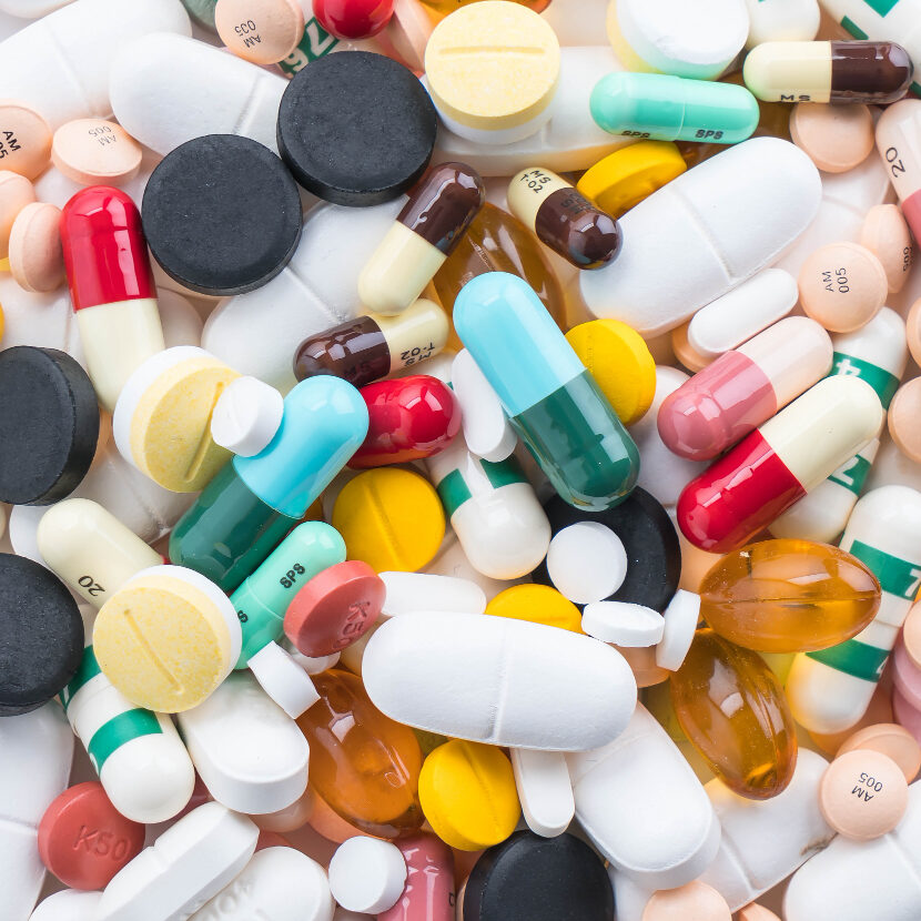 Tabletten en capsules met verschillende kleuren en vormen, medicatie en supplementen voor schildkliergezondheid.